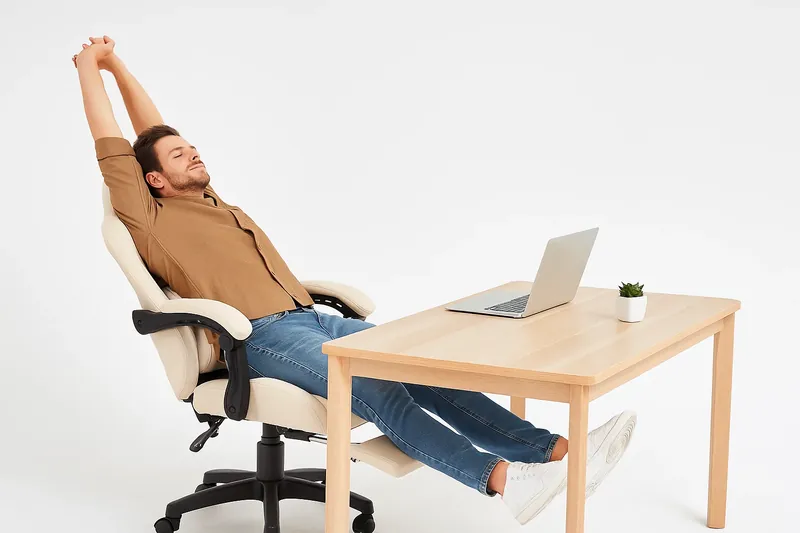 Man reclining in Dowinx gaming chair with footrest extended under modern wooden desk, demonstrating 135-degree relaxing mode setup for ergonomic comfort in 2025 home office.